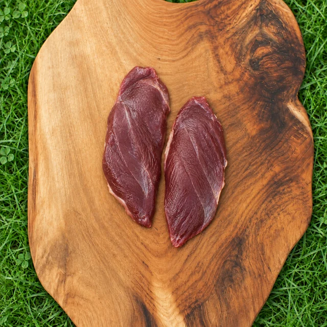 Ganzenborstfilet: twee filets van grauwe gans op een houten plank in het gras