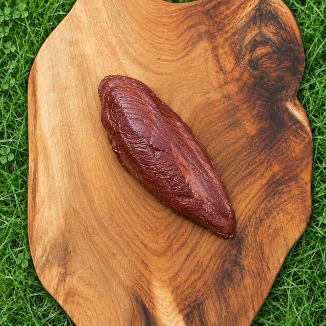 Gerookte ganzenborst: een hele gerookte borst op een houten plank in het gras